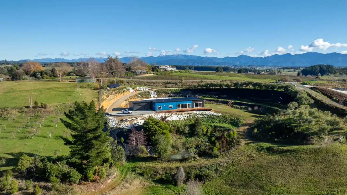 Aerial view of an energy-efficient Ecotectural home on a rural Tasman site with the mountains beyond
